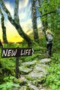 New Life Arrowed Wooden Sign in Forest with Person and Sunset. Royalty Free Stock Photo