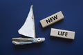 New life symbol. Wooden blocks with words New life. Beautiful deep blue background with boat. Business and New life concept. Copy Royalty Free Stock Photo