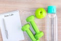 New life written on Notebook and dumbbells, fruit, drink water on wooden surface.