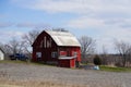 New Lisbon, Wisconsin USA - April 23rd, 2022: Abandoned red barn house sits on hillside out on the countryside