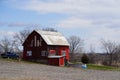 New Lisbon, Wisconsin USA - April 23rd, 2022: Abandoned red barn house sits on hillside out on the countryside