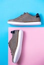 New male's stylish sneakers made of grey canvas on a pink-blue background. Flat lay. Copy space. Side view of shoes Royalty Free Stock Photo