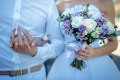 New marriage couple. Bride with wedding bouquet holds the groom`s arm. Stylish newlyweds. Wedding concept