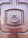 New metal doorknocker on wooden closed brown door