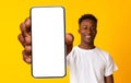 New mobile app ad. African american man showing white empty cellphone screen, recommending website or ad, mockup