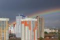 New modern block multistory house on dark sky background in four colors: red, orange, grey and white. Bad weather and rainbow. Royalty Free Stock Photo