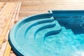 New modern fiberglass plastic swimming pool entrance step with clean fresh refreshing blue water on bright hot summer