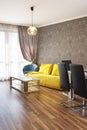 New modern living room. New home. Interior photography. Wooden floor. Dining table with set of chairs, yellow sofa Royalty Free Stock Photo