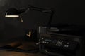 New modern printer, notebook and lamp on wooden table at night Royalty Free Stock Photo