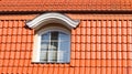 New, modern roof made of red ceramic tiles and a large attic window.