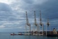 New modern very high gantry cranes in vertical position waiting for cargo operation under dramatic sky.