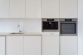 New modern white kitchen with built in oven and chrome water tap. Royalty Free Stock Photo