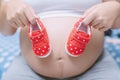 New mom Pregnant woman hand show small shoes baby Prepare red shoes