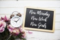 New Monday, New Week, New Goals text message with alarm clock and flower decoration on wooden background Royalty Free Stock Photo