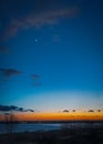 New moon and venus over Pegwell Bay just after sunset when the sky is a Depp blue with an intense orange and red glow Royalty Free Stock Photo