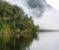 A new morning dawning at Doutful Sound, clouds hanging low in the mountains, Fiordland National Park, New Zealand