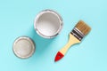 New natural bristle brush with wooden handle, open white paint can and lid on a cyan blue background. Construction painting work, Royalty Free Stock Photo