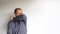 New normal. Closeup headshot portrait petrified young handsome man in a grey wear sneezes on the elbow, isolated on beautiful Royalty Free Stock Photo