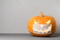New normal concept. Glowing Halloween pumpkin in a protective medical mask on a gray background.
