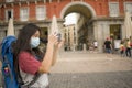 New normal holidays travel in Europe - young beautiful and happy Asian Chinese tourist woman with face mask and backpack taking Royalty Free Stock Photo