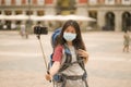 New normal holidays travel in Europe - young happy and beautiful Asian Chinese tourist woman in face mask taking selfie with Royalty Free Stock Photo