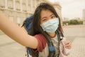 New normal holidays travel in Europe - young happy and beautiful Asian Japanese tourist woman wearing mask taking selfie with Royalty Free Stock Photo
