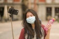 New normal holidays travel in Europe - young happy and beautiful Asian Korean tourist woman in face mask taking selfie with mobile Royalty Free Stock Photo