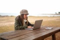 New normal job activities using internet connection outdoor: young Caucasian woman sitting at a wooden table in a sea park working