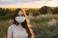 New normal, lockdown, face mask. Outdoor portrait of woman in protective face Statement Masks with flowers on nature