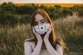 New normal, lockdown, face mask. Outdoor portrait of woman in protective face Statement Masks with flowers on nature