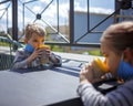 New normal reality, stay safe in street cafe, kids with medical mask waiting for breakfast Royalty Free Stock Photo