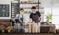 New normal startup small business of coffee shop concept. Male and female barista in face mask and standing behind bar counter in Royalty Free Stock Photo