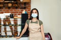 New normal, startup and small business at covid-19 quarantine. Latin female barista in apron and protection mask Royalty Free Stock Photo