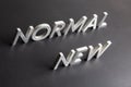 new normal word composed of silver metal letters on a flat matt black surface with diagonal perspective