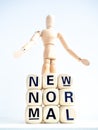 New Normal, words on wooden alphabet cube and wooden figure Royalty Free Stock Photo