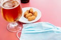 Glass of beer and a plate of tapas with a mask on the table Royalty Free Stock Photo
