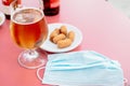 Glass of beer and a plate of tapas with a mask on the table Royalty Free Stock Photo