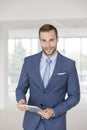 Portrait of confident handsome young businessman standing with digital tablet in new office Royalty Free Stock Photo