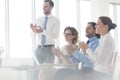 Smiling business colleagues applauding while sitting at table in new office during meeting Royalty Free Stock Photo