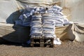 New and old partially broken white sandbags used for flood protection put on wooden pallets next to temporary flood protection