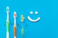 New and old toothbrushes in the form of cartoon characters on a blue background with a smile drawn with toothpaste.