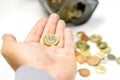 The new one pound British currency coins on hand and blurry coins open from the piggy bank laid out scattered on white background Royalty Free Stock Photo