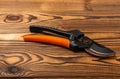 New orange garden pruners on a brown wooden background.