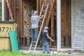 Two Workers Removing Siding From Old Home