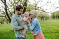 New parents holding small toddler, baby, outdoors in spring nature. Older First-time parents. Royalty Free Stock Photo