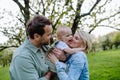 New parents holding small toddler, baby, outdoors in spring nature. Older First-time parents. Royalty Free Stock Photo