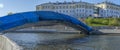 New pedestrian bridge construction over river in city. Construction site. Blue sky.