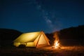 Camping tent under starry night sky with campfire glowing, peaceful travel adventure scene Royalty Free Stock Photo