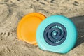 New plastic frisbee discs on sandy beach, closeup