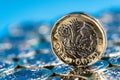 New pound coin introduced in the UK in 2017, front, standing on a layer of coins and on a blue background Royalty Free Stock Photo